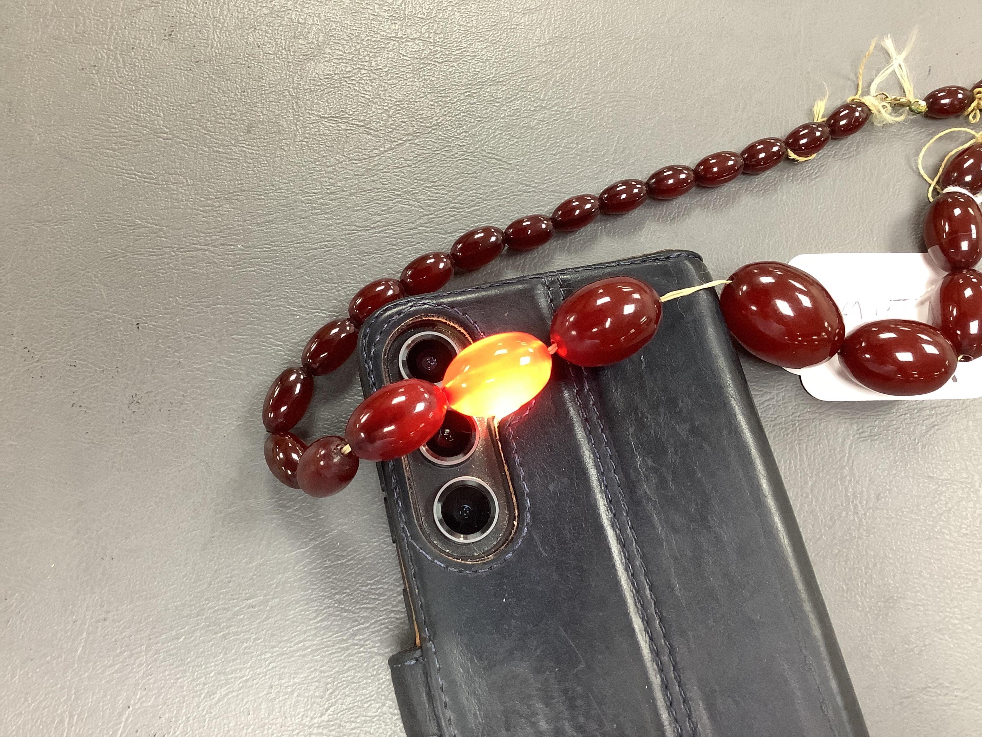 A cherry-coloured bakelite imitation amber necklace, composed of graduated oval beads measuring approximately 1.2-3cm, length 56cm, gross weight approximately 54 grams